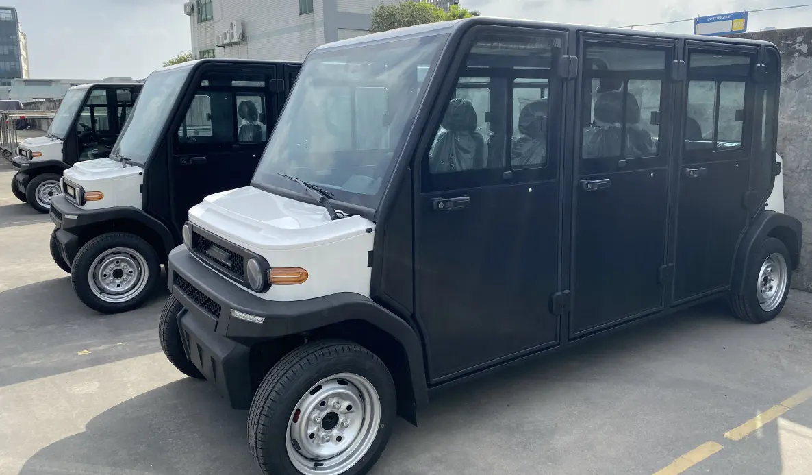 Black and white utility vehicle parked on a concrete surface with other similar vehicles in the background.