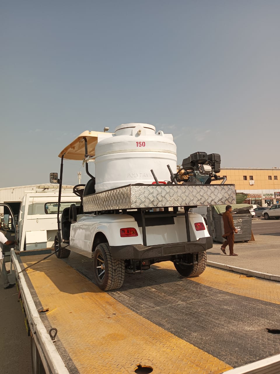 White utility truck with large tank on a flatbed trailer