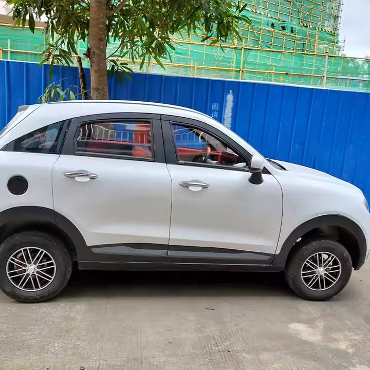 White SUV parked on a concrete surface with a blue fence and greenery in the background