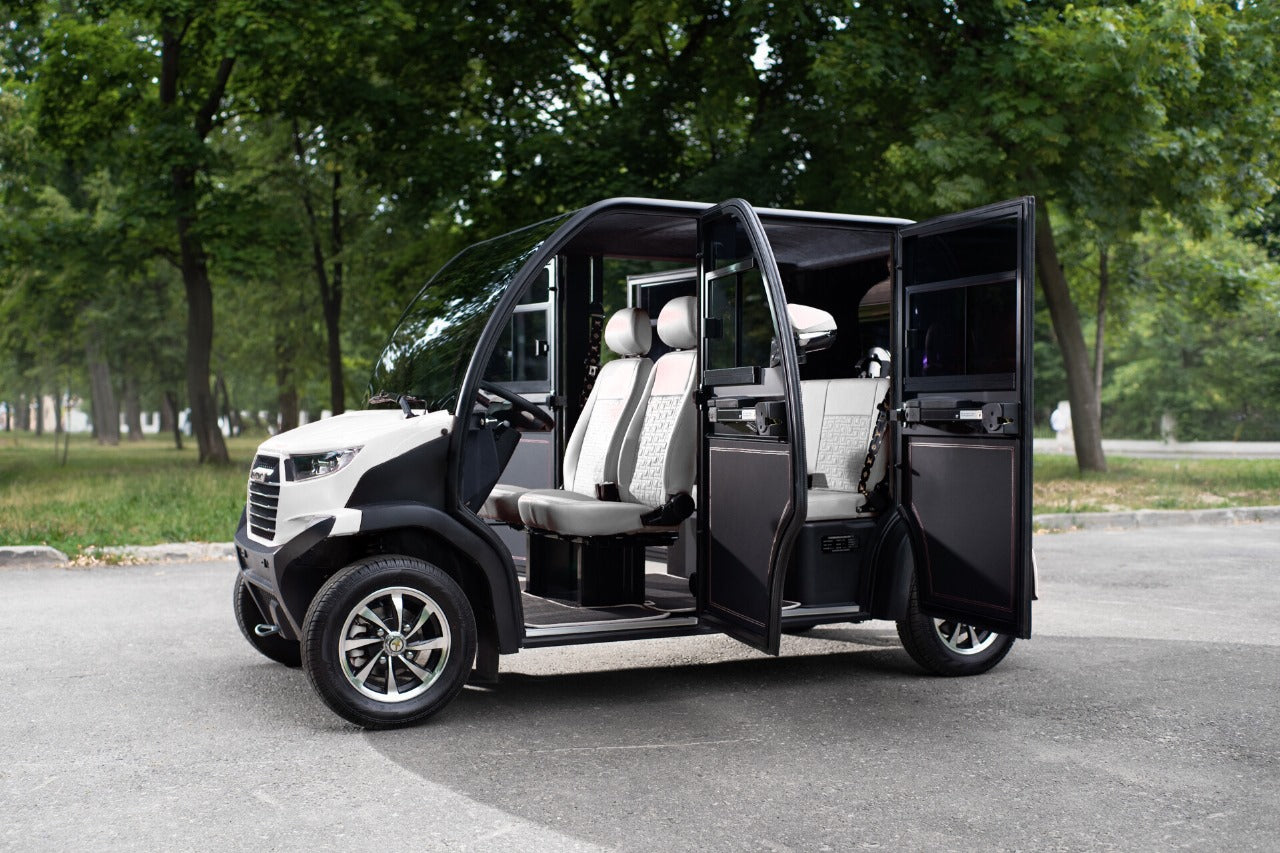 Black and white electric vehicle with open doors on a road with trees in the background