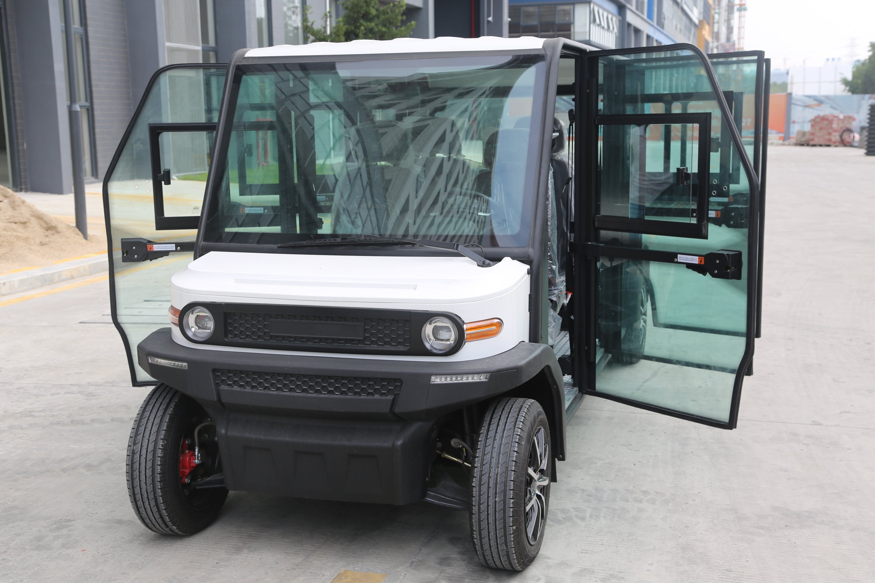 White electric vehicle with open doors on a paved road