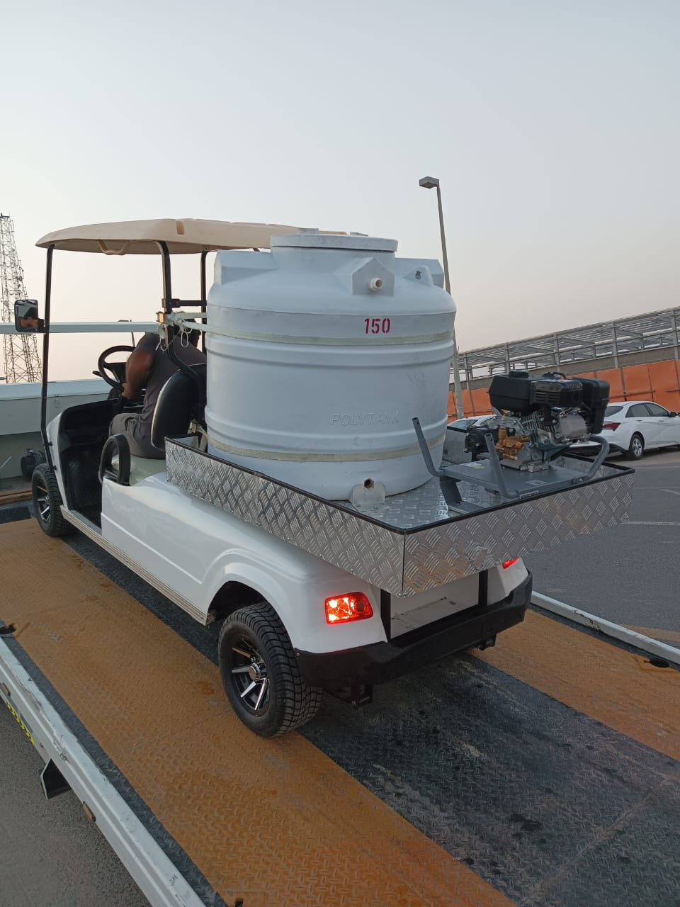 Golf cart with a large white tank on a flatbed truck