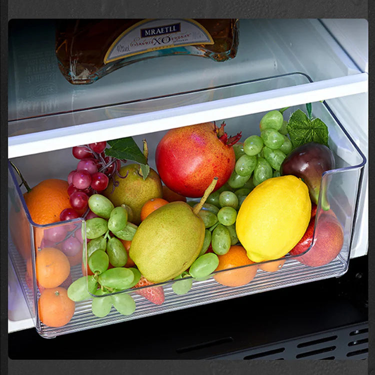Open refrigerator door showing a fruit drawer with fruits and a bottle of wine.