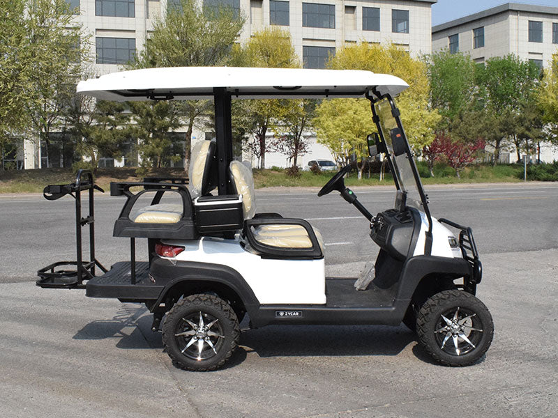White and black golf cart on a paved road with buildings and trees in the background